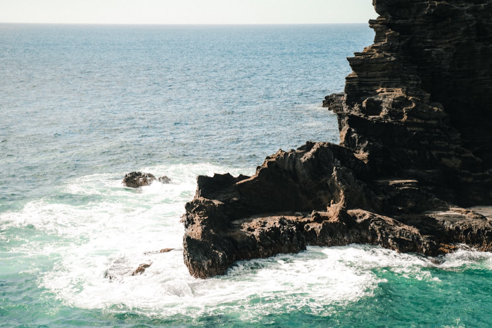 waves crashing on rock formation during daytime