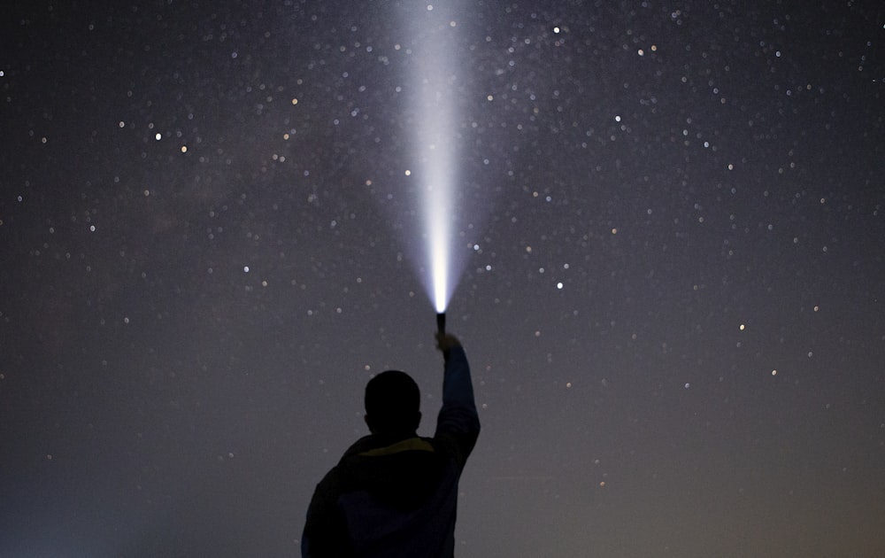 man raising flashlight