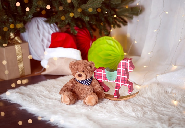 A cozy scene featuring a plush reindeer with a red scarf sitting on a wooden shelf.