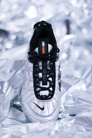 Close-up of a sleek black sneaker with vibrant orange accents on a clean white background.