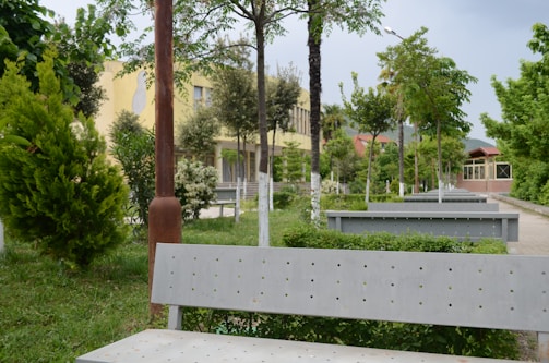 A serene open green space with benches and flowering plants under a blue sky