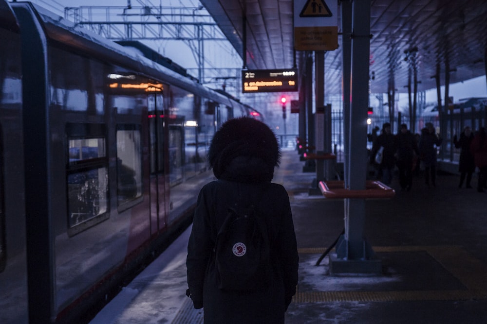 a person standing at a train station waiting for a train