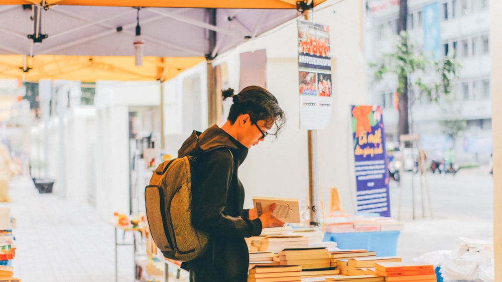 man holding book beside books