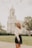 woman wearing white long-sleeved crop top standing near road viewing white church during daytime
