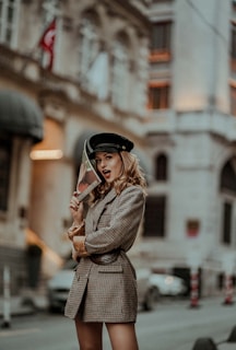 A candid street-style shot of a woman wearing a tailored blazer and silk scarf, walking confidently in soft natural light.