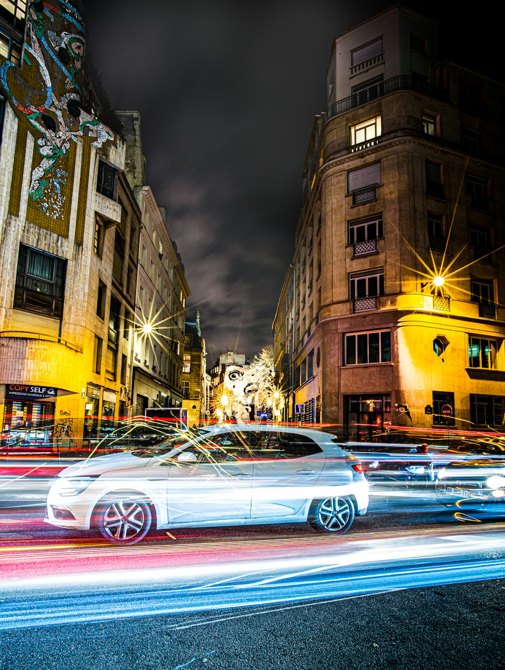 time lapse photography of vehicles on road near high-rise buildings during night time