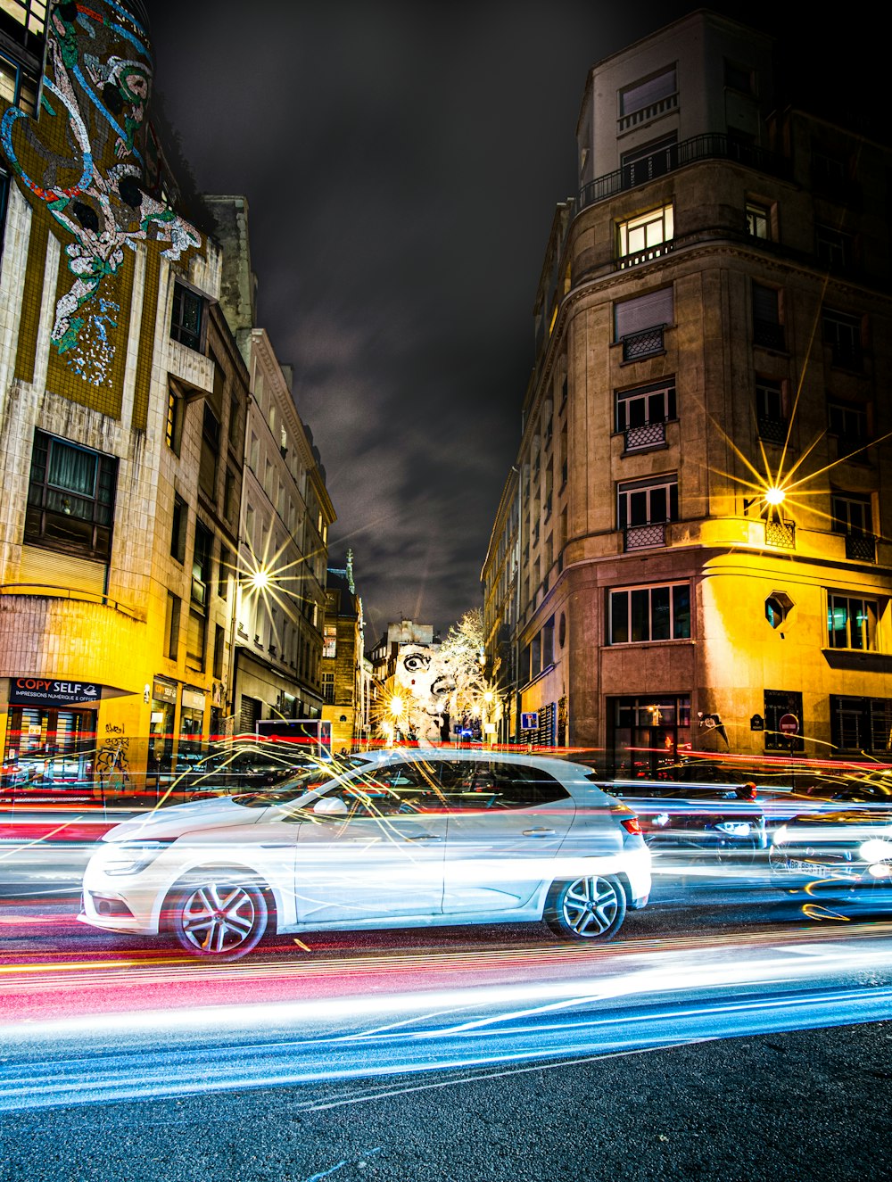 Zeitrafferfotografie von Fahrzeugen auf der Straße in der Nähe von Hochhäusern während der Nacht