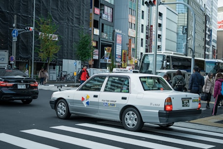A sleek taxi car waiting outside a busy city street with a driver ready to assist.