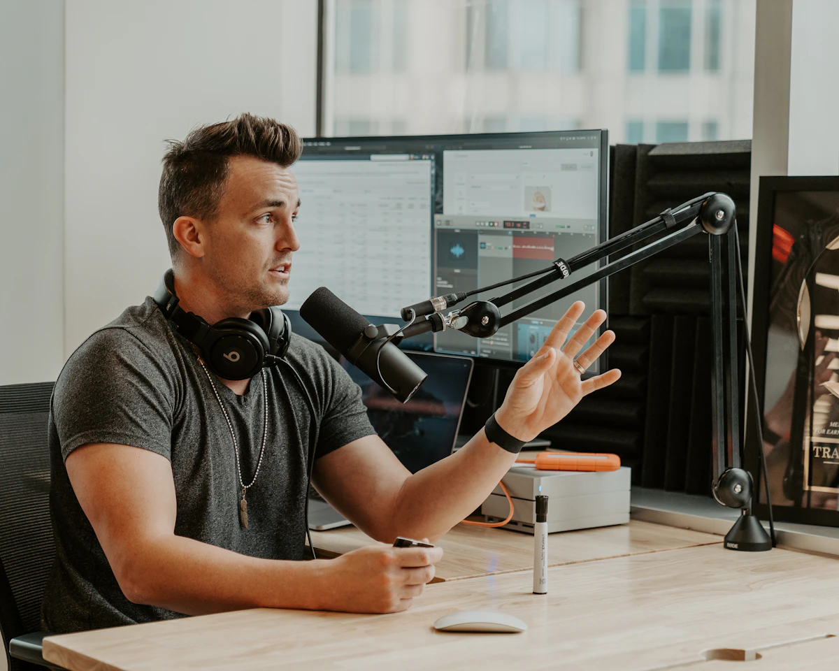 A podcast guest wearing headphones explains a point into a studio microphone during a relaxed interview