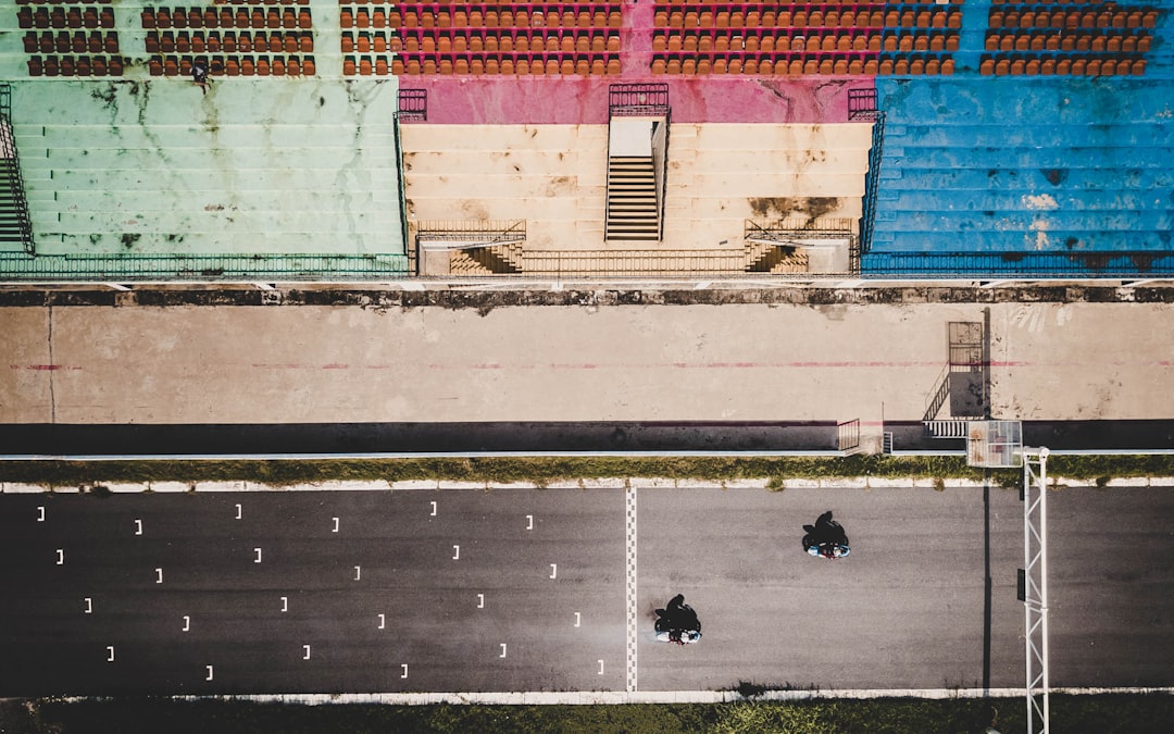 two persons riding motorcycles on road near building