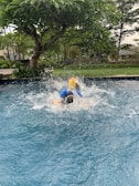 A child diving into the water with a big splash.
