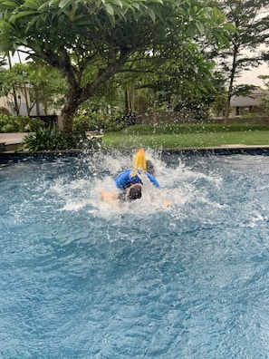 A child diving into the water with a big splash.