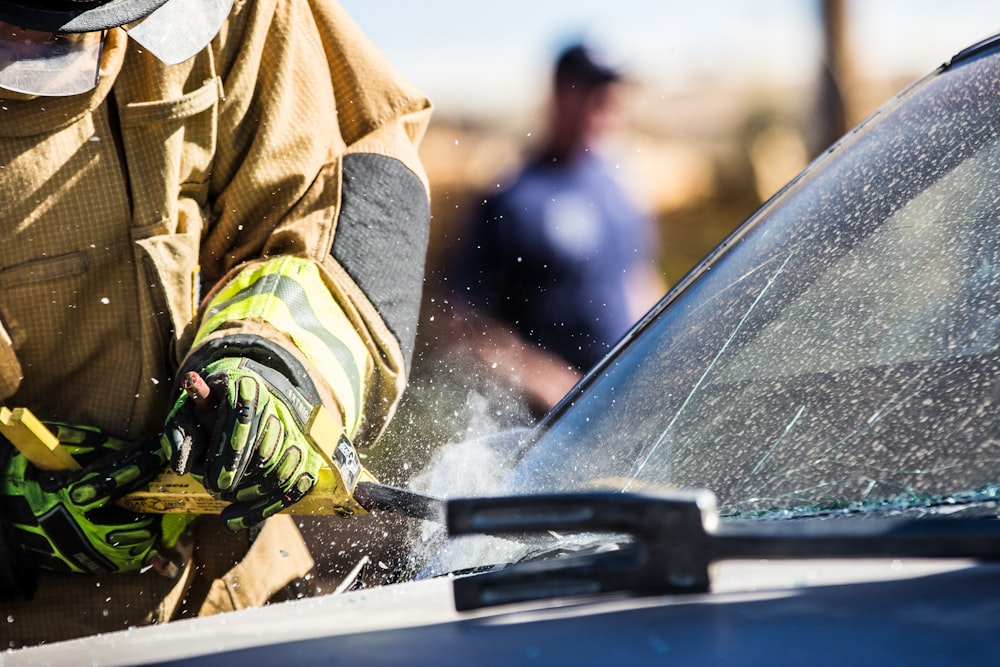 a man in a fireman's uniform sanding a car