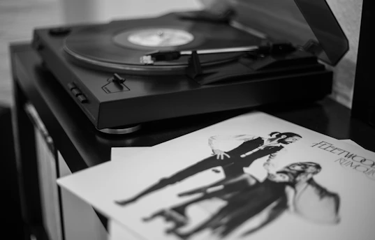 A grainy black-and-white photo of a small, intimate gathering around a vintage record player.