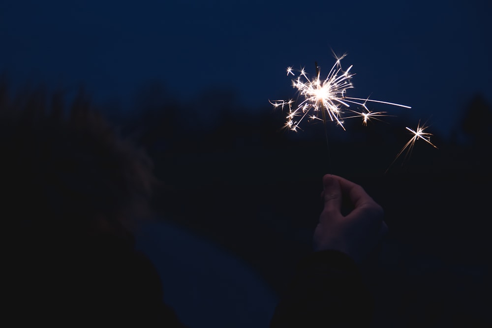 a person holding a sparkler in their hand at night