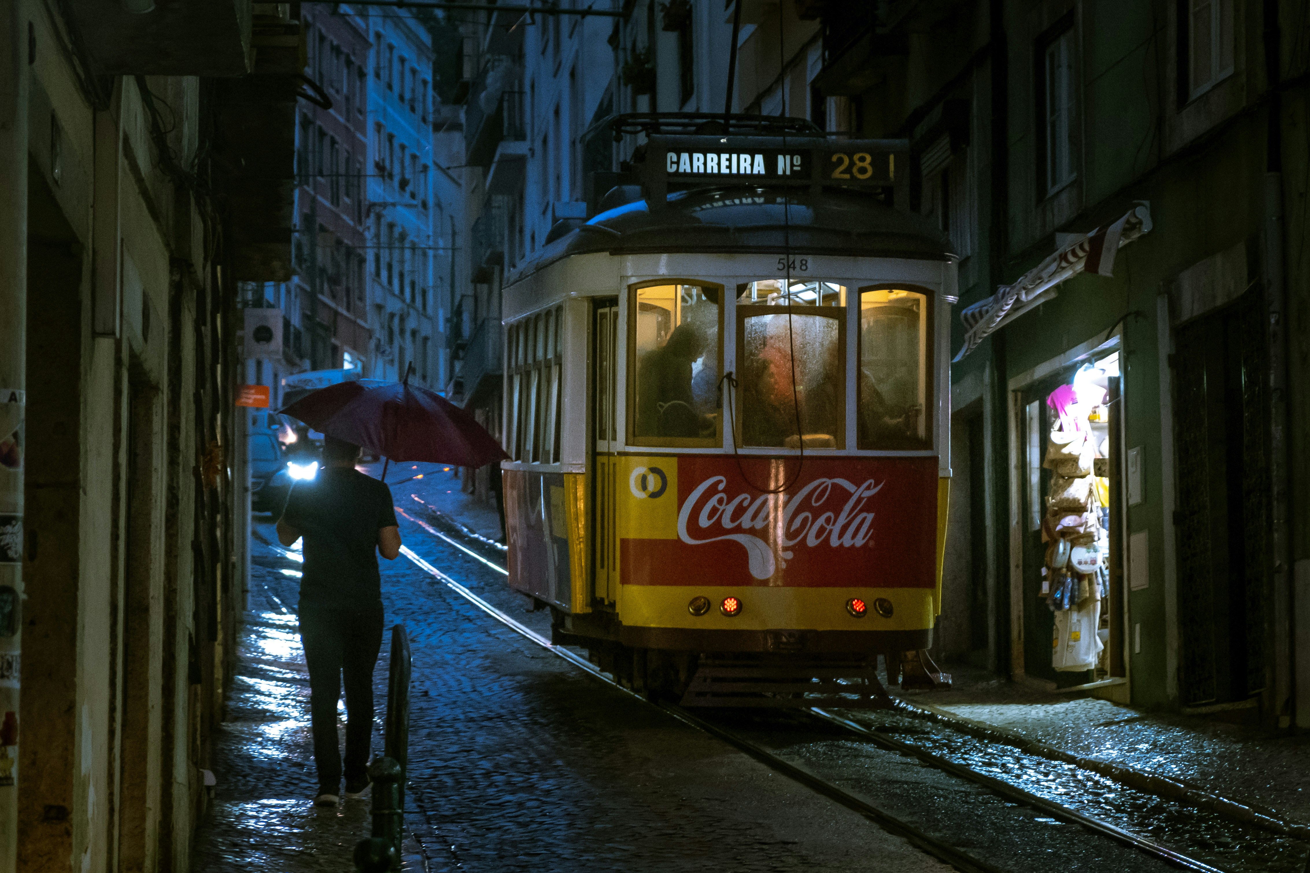 A tram in Lisbon rolling uphill on a rainy night.