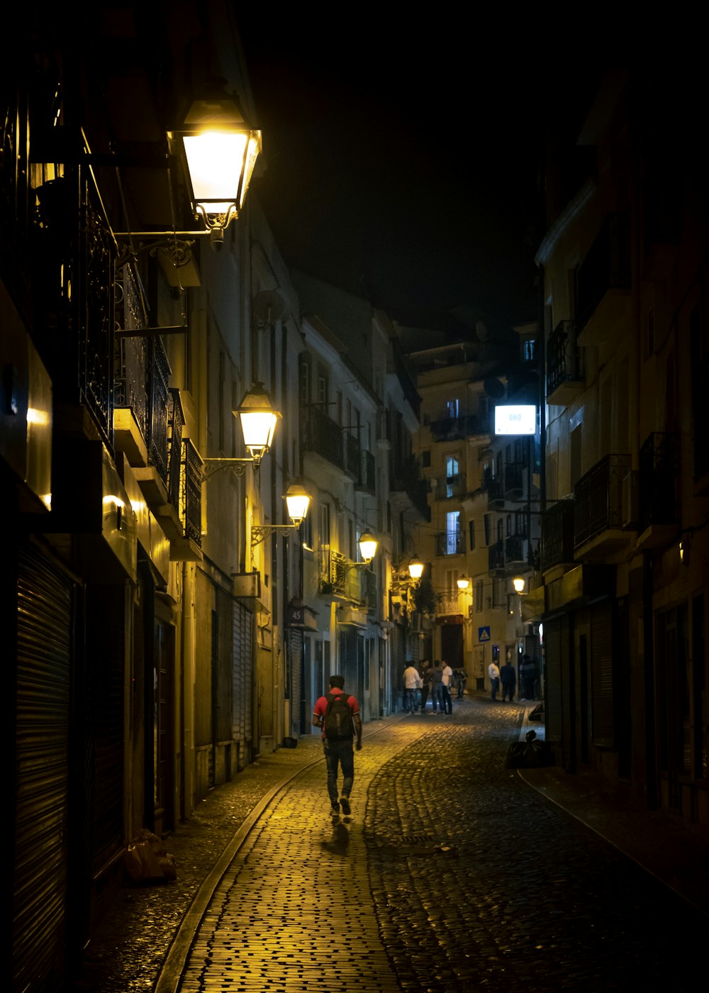 a man walking down a cobblestone street at night