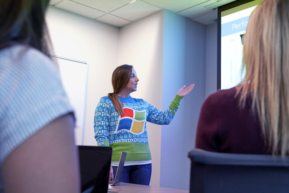 woman in blue sweater standing beside projector screen