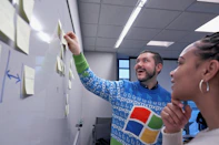 A smiling consultant presenting branding ideas to a small business owner in a bright office.