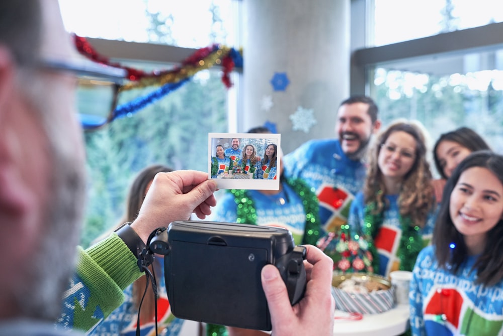 man holding photo of men and women wearing Windows sweater