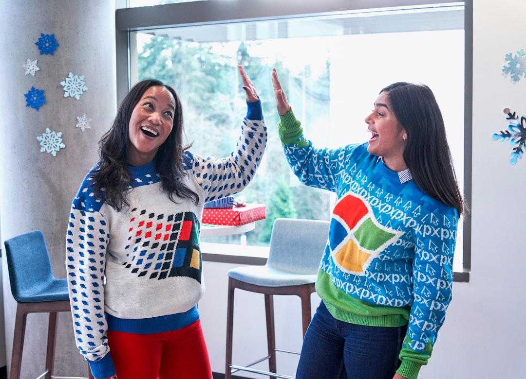 two women in white and blue sweaters doing high five