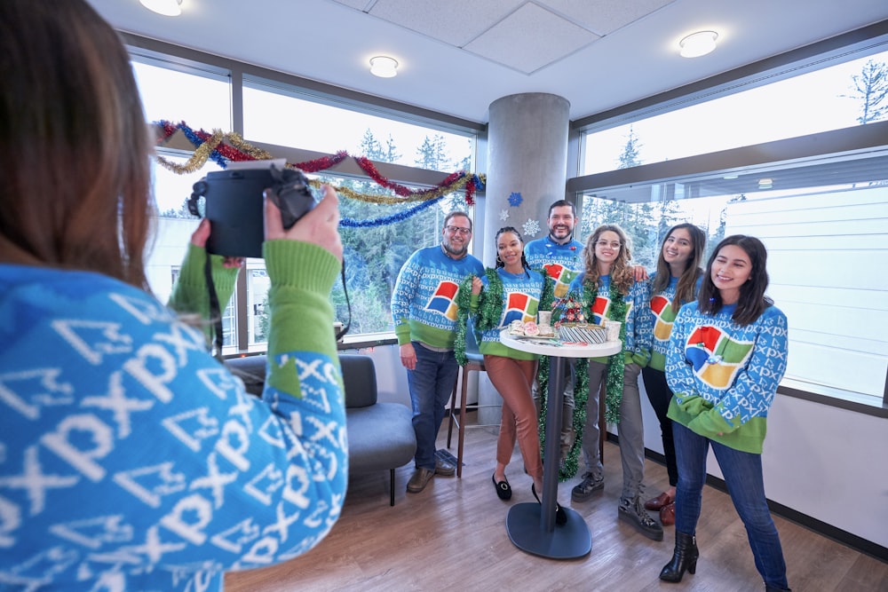 woman taking picture of family wearing Windows XP sweater inside well-lit room