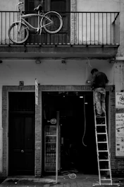 grayscale photography of man on ladder