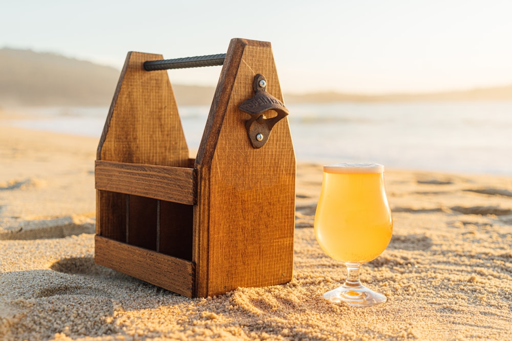 brown wooden tool box beside clear wine glass on sand