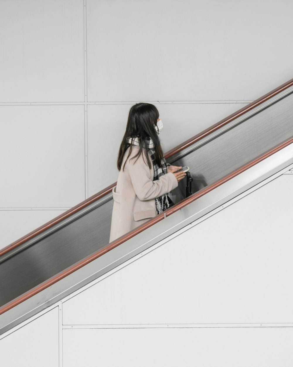 Frau im grauen Mantel in der Rolltreppe