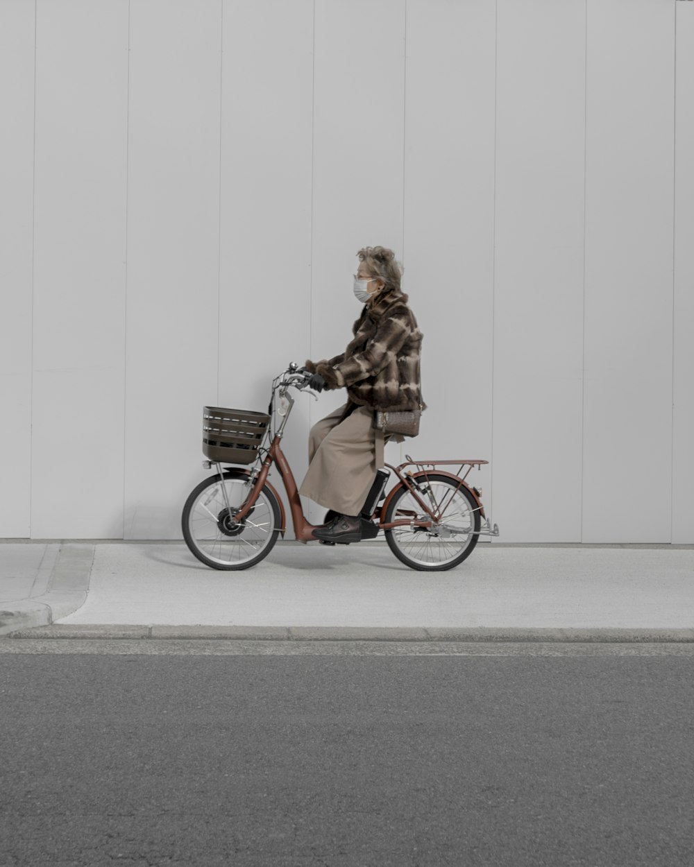 woman riding city bike near wall and road