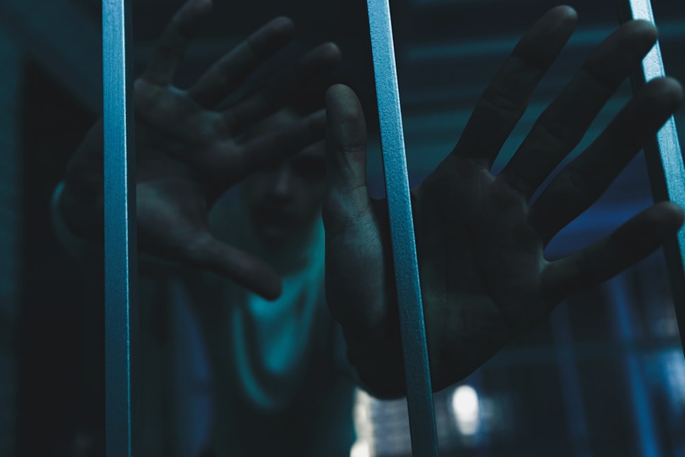 a person holding their hands out through bars