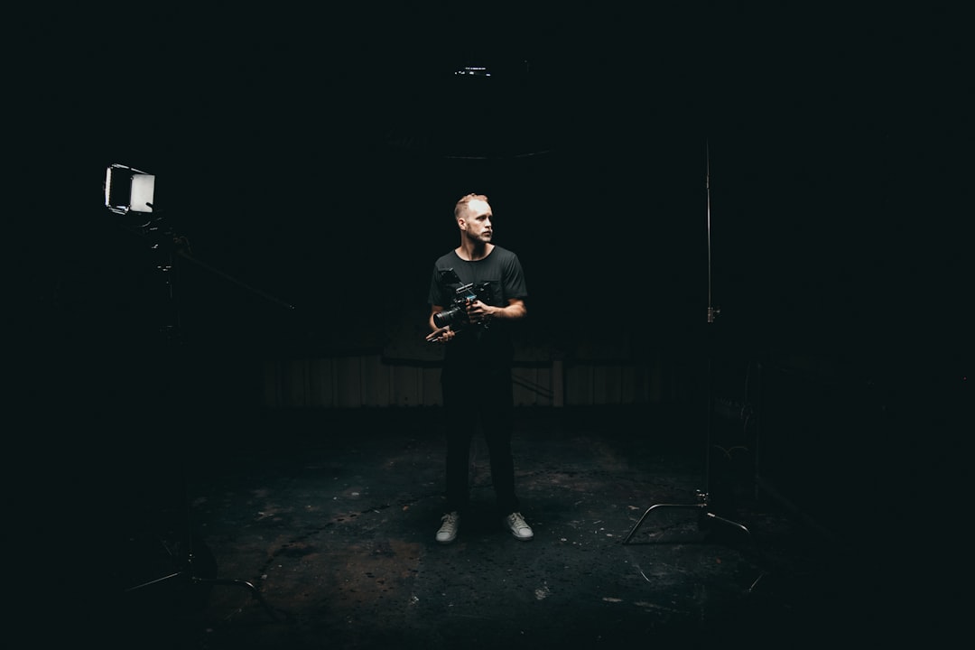 man standing inside dark room while holding camera