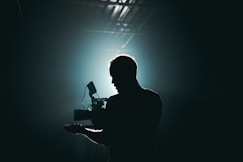 silhouette photography of man holding camera