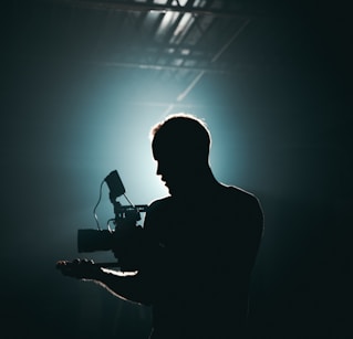 silhouette photography of man holding camera