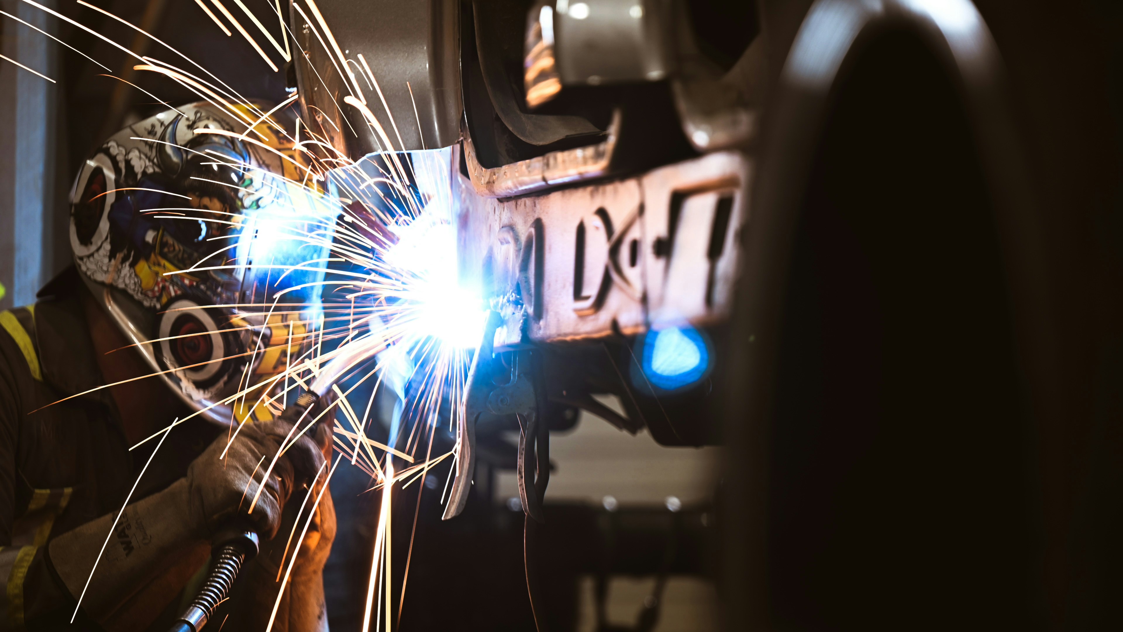 a welder working on a car with a lot of sparks
