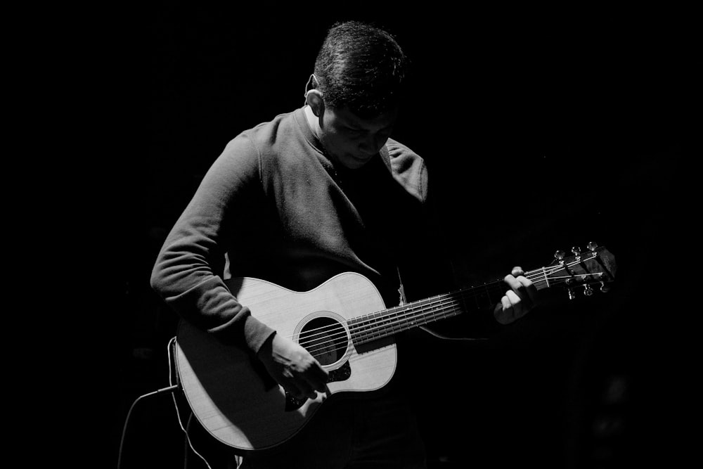 grayscale photography of man playing guitar