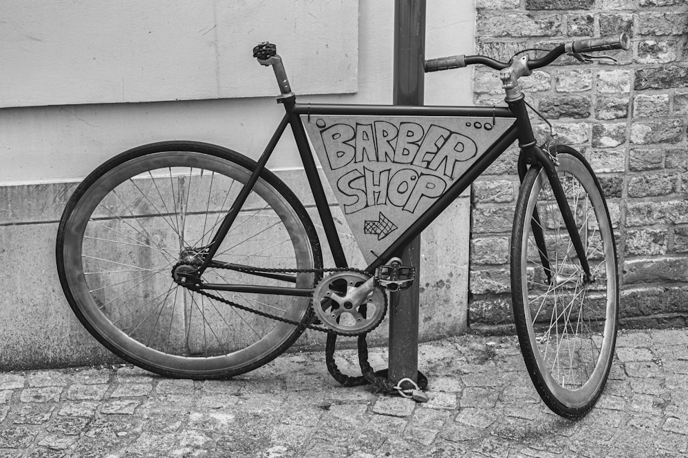 Bicicleta rígida negra estacionada al lado de la pared