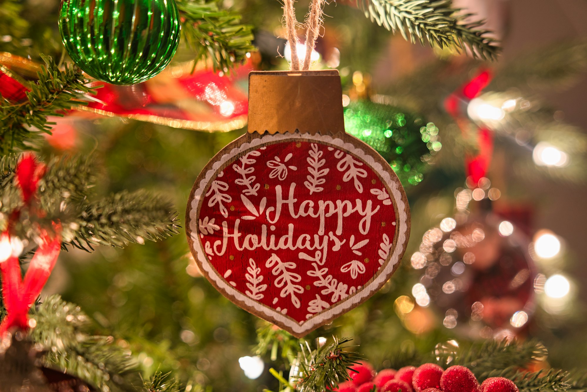 A macro shot of a "Happy Holidays" Christmas tree ornament
