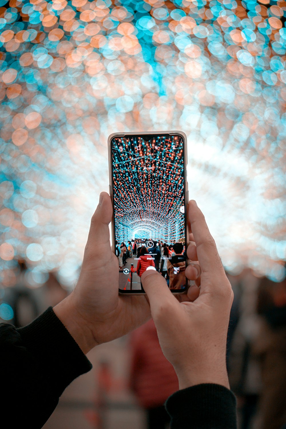 unknown person holding black smartphone capturing string lights