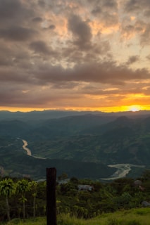 Panoramic view of a scenic valley with winding rivers and distant peaks at sunset.