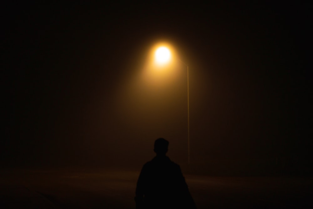 Ein Mann, der im Dunkeln unter einer Straßenlaterne steht