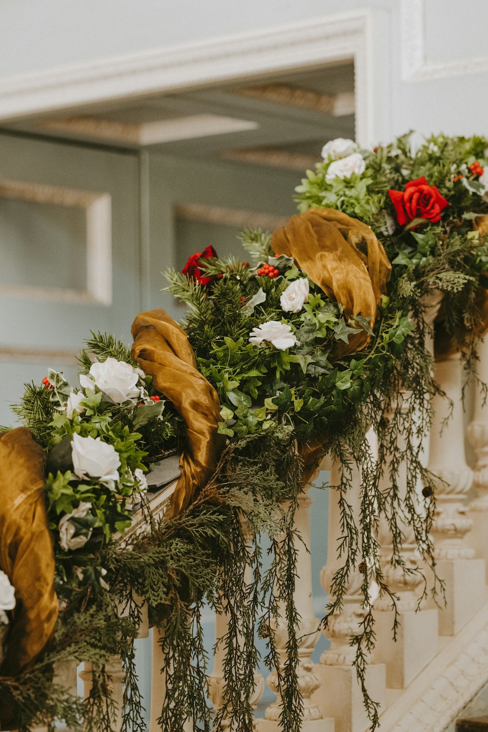 green wreath with red and white rose on handrail