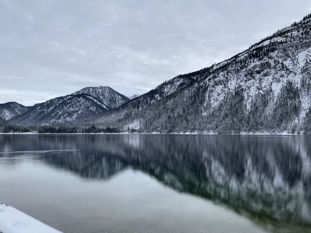 snow-covered hill near calm water