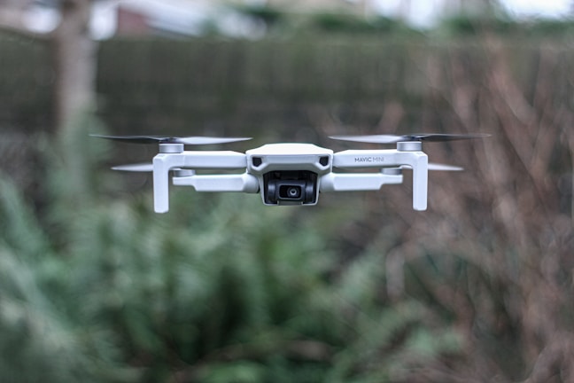 white camera drone flying over green leafed plant