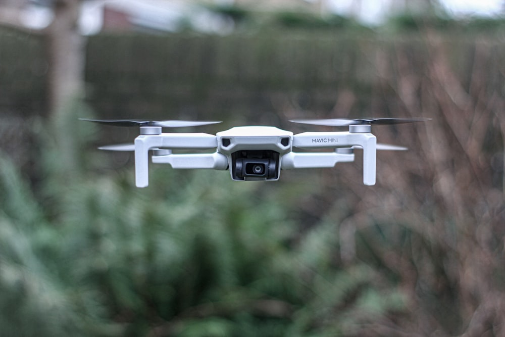 white camera drone flying over green leafed plant