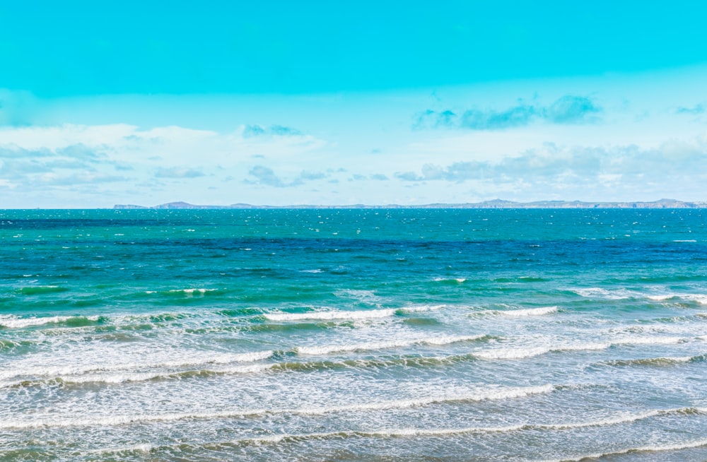 body of water crashing on shore during daytime