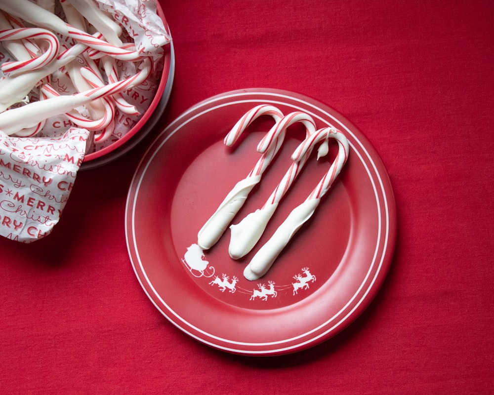 빨간 접시에 흰색과 빨간색 사탕 지팡이
