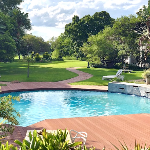 swimming pool with brown frame and pathway near trees during day