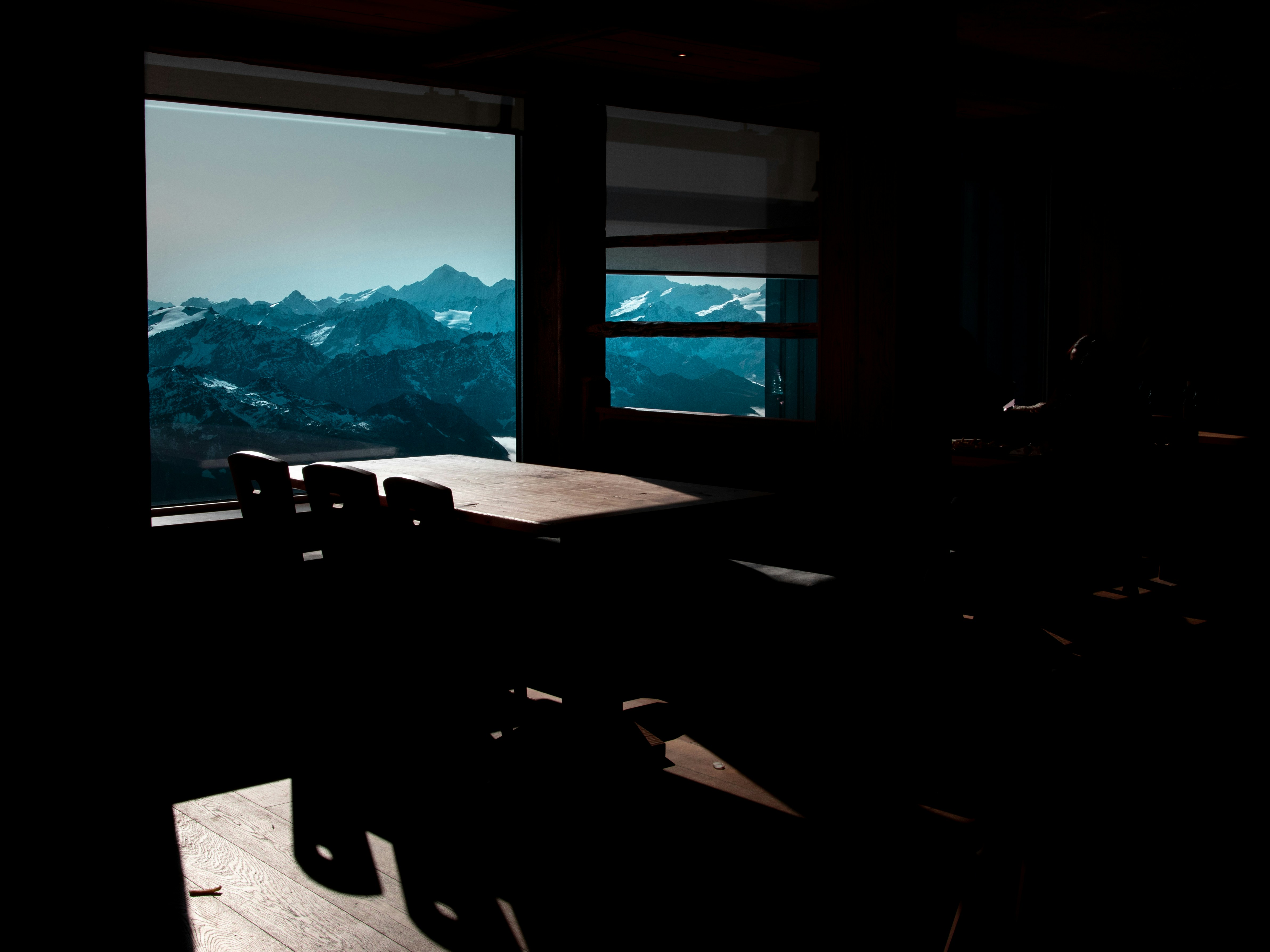 brown wooden table beside window overlooking rocky mountain, 