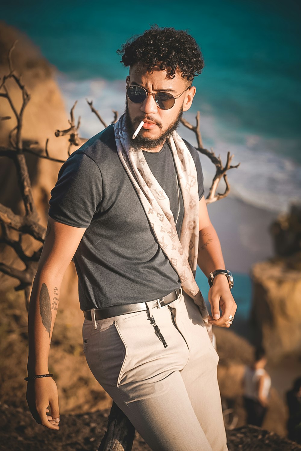 man in gray shirt, white jeans, leaning on brown wood branch